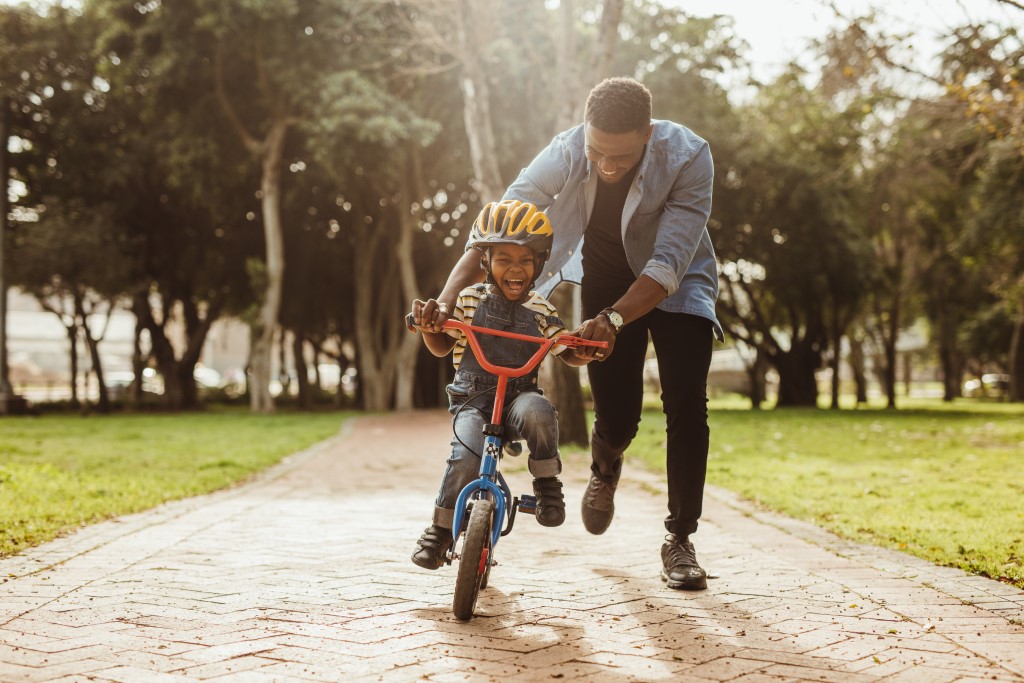 father teaching his son cicyling at park