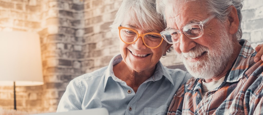 senior age couple sitting together looking at laptop