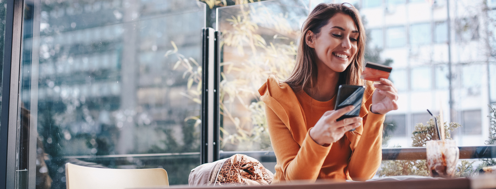 Woman looking at credit card and using her phone. 