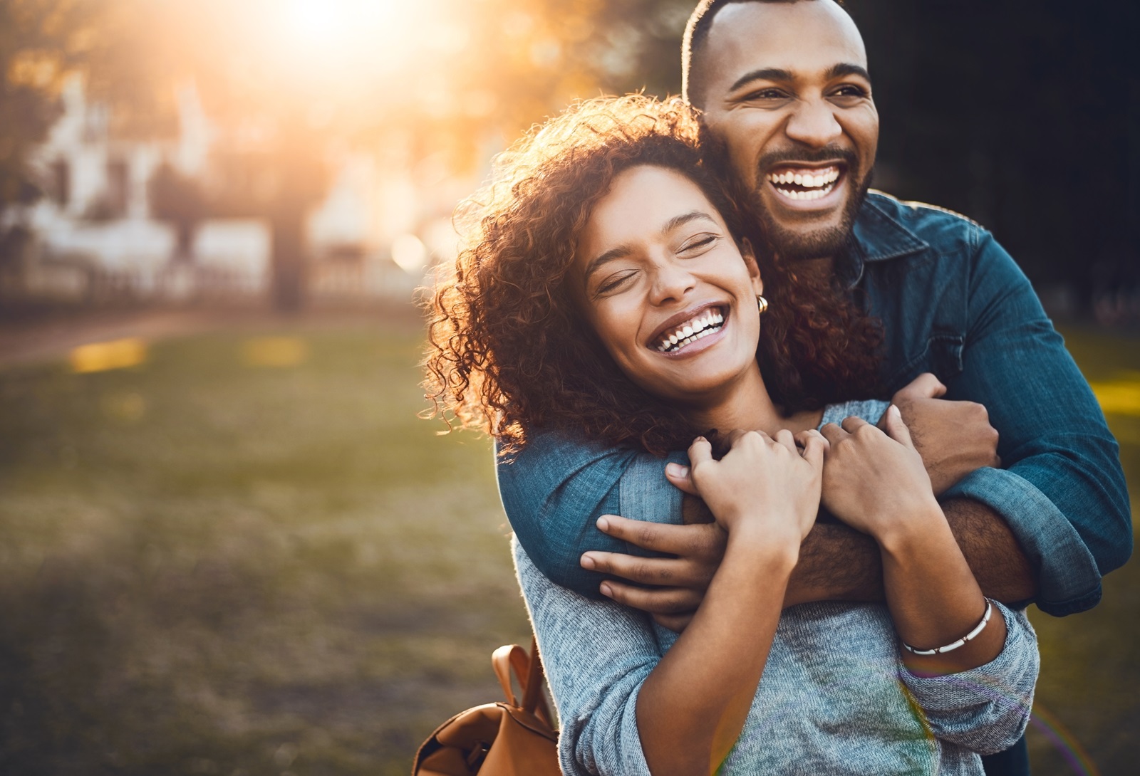 A young couple embraces outside under the sunset.